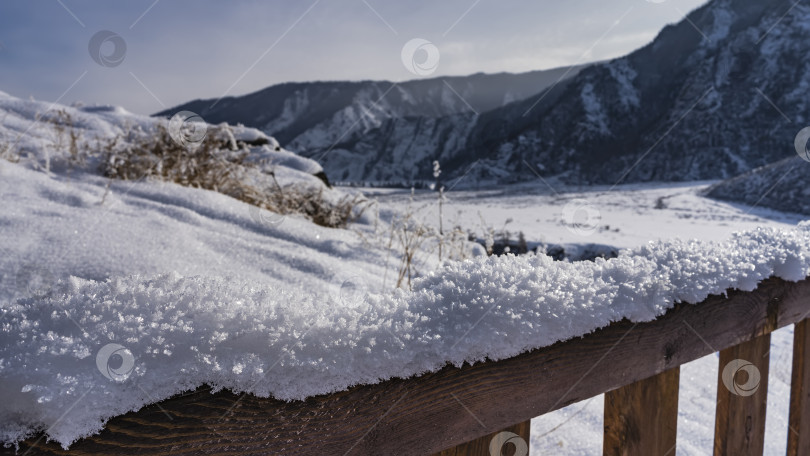 Скачать На некрашеных деревянных перилах лежит слой чистого белого снега. фотосток Ozero