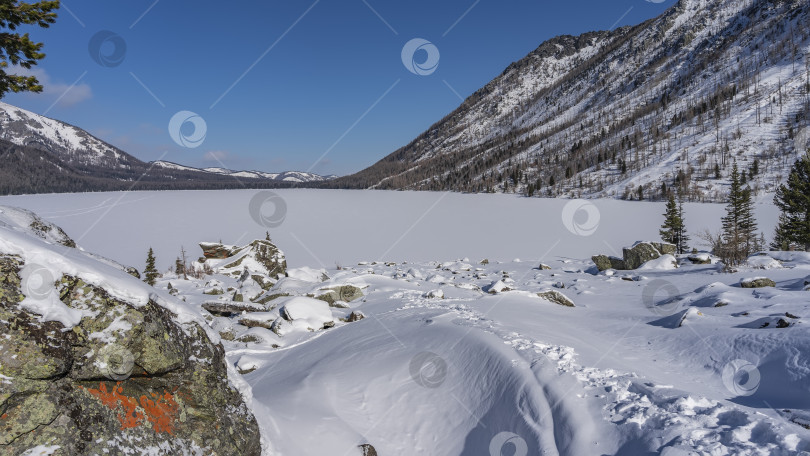Скачать Замерзшее озеро, окруженное горами, покрыто нетронутым белым снегом фотосток Ozero