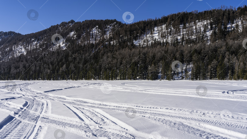 Скачать В заснеженной долине видны пересекающиеся следы шин и снегоходов фотосток Ozero