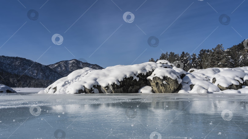 Скачать На берегу замерзшей реки расположены живописные валуны, покрытые слоем снега. фотосток Ozero
