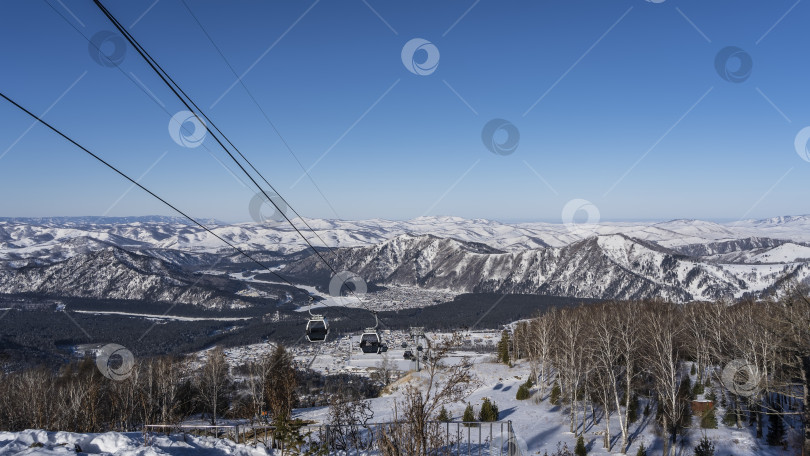 Скачать Канатная дорога проходит над заснеженной высокогорной долиной. фотосток Ozero