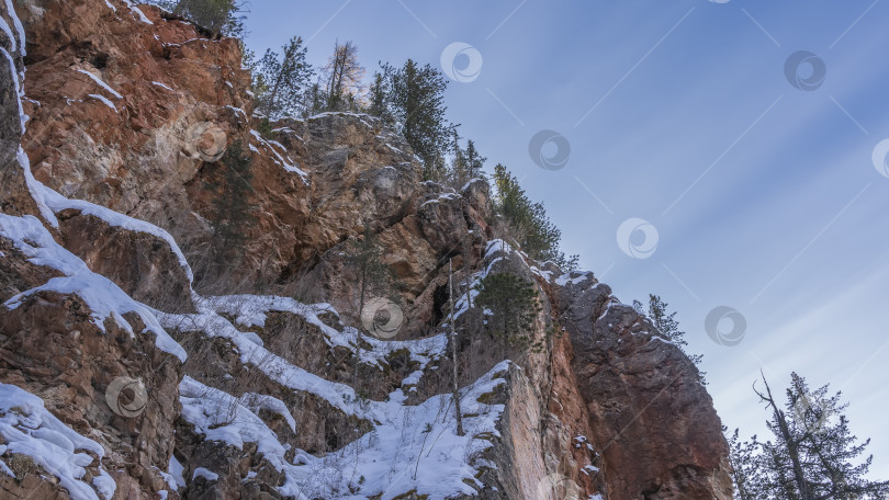 Скачать На крутых красно-коричневых склонах утеса лежит слой снега. фотосток Ozero