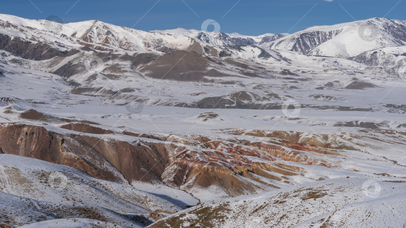 Скачать Склоны оранжевых и коричневых холмов покрыты снегом. фотосток Ozero