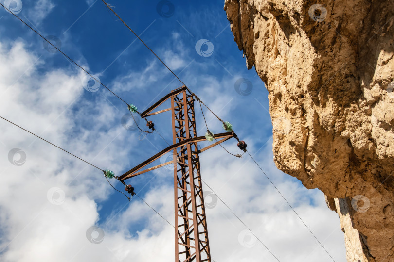 Скачать Столбы линии электропередачи проложены в горной местности на большой высоте фотосток Ozero