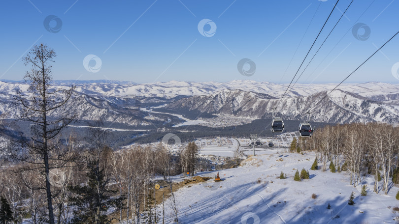 Скачать Кабины фуникулера движутся по канатам над заснеженной долиной. фотосток Ozero