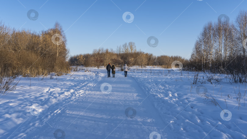 Скачать Три человека уходят по тропинке, протоптанной в снегу. фотосток Ozero