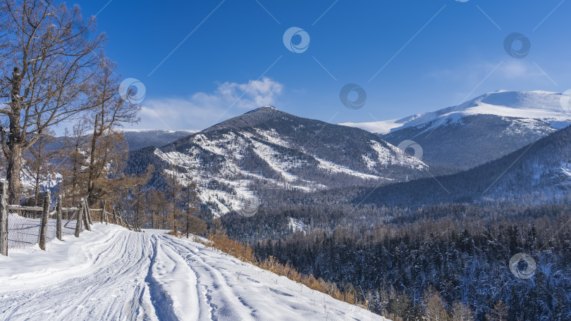 Скачать Дорога, протоптанная в снегу, тянется вдоль склона холма. фотосток Ozero