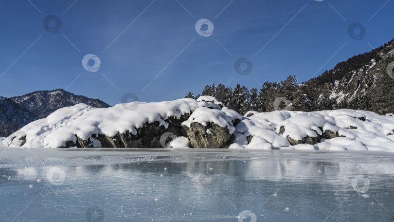 Скачать Живописные валуны у берега замерзшей реки покрыты слоем чистого снега. фотосток Ozero