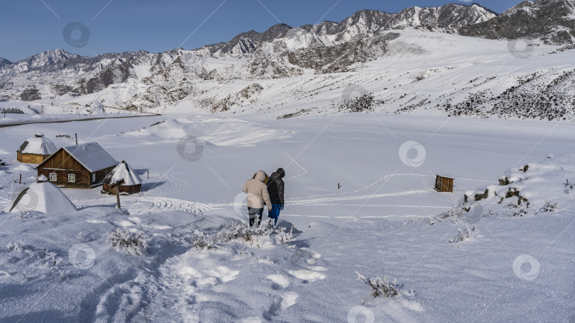 Скачать Два человека спускаются с заснеженного холма. фотосток Ozero