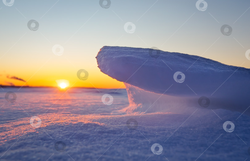 Скачать Вид на заснеженное замерзшее озеро на закате. Осколки льда скапливаются фотосток Ozero