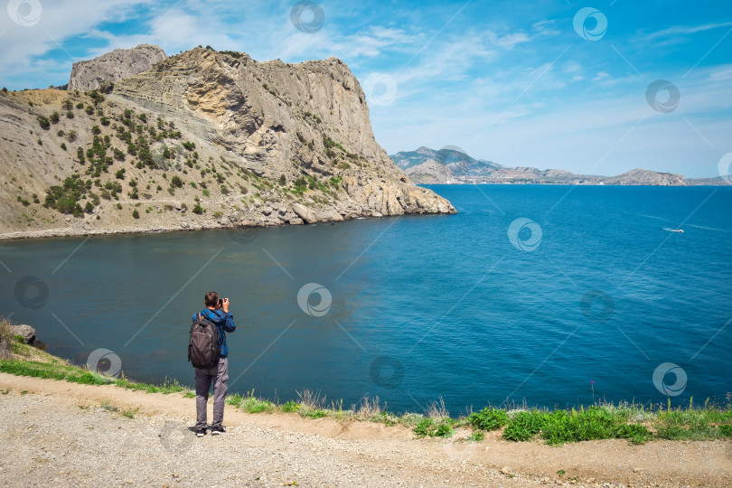 Скачать Взрослый мужчина с фотоаппаратом стоит на краю фотосток Ozero