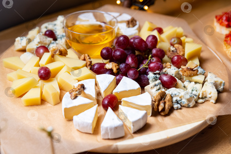 Скачать Сырное ассорти с виноградом, орехами и медом на деревянном столе фотосток Ozero