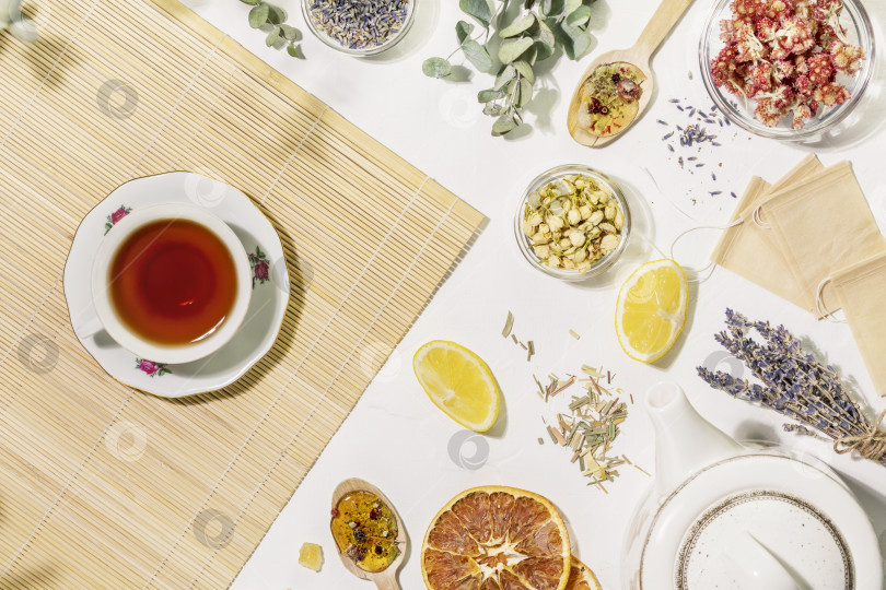 Скачать Плоская тарелка с сухими цветами и травами, бумажными пакетиками чая, чайником и чашкой чая фотосток Ozero