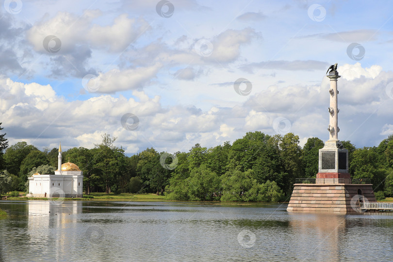 Скачать Россия, Санкт-Петербург, 10 июля 2020 года, Екатерининский парк. На фотографии изображены турецкая баня и Чесменская колонна на берегу озера в центральной части Екатерининского парка фотосток Ozero