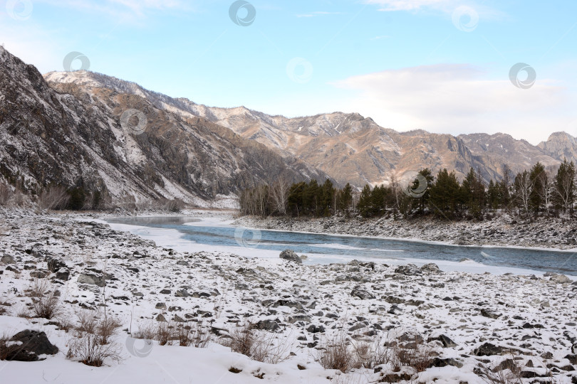 Скачать Заснеженный скалистый берег красивой реки, протекающей по зимней горной долине. фотосток Ozero