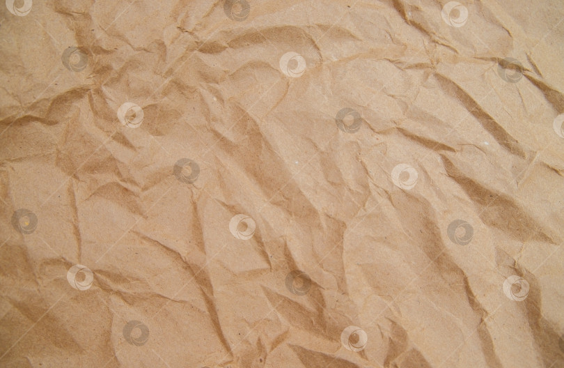 Скачать Фон и текстура выполнены из мятой бежевой крафт-бумаги. Оберточная бумага для посылок и подарков. фотосток Ozero