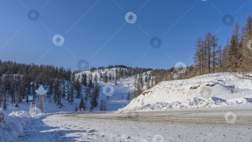 Скачать Шоссе огибает заснеженный холм. фотосток Ozero