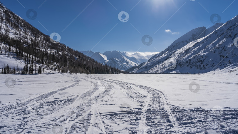 Скачать На заснеженной поверхности замерзшего озера видны пересекающиеся следы снегоходов. фотосток Ozero