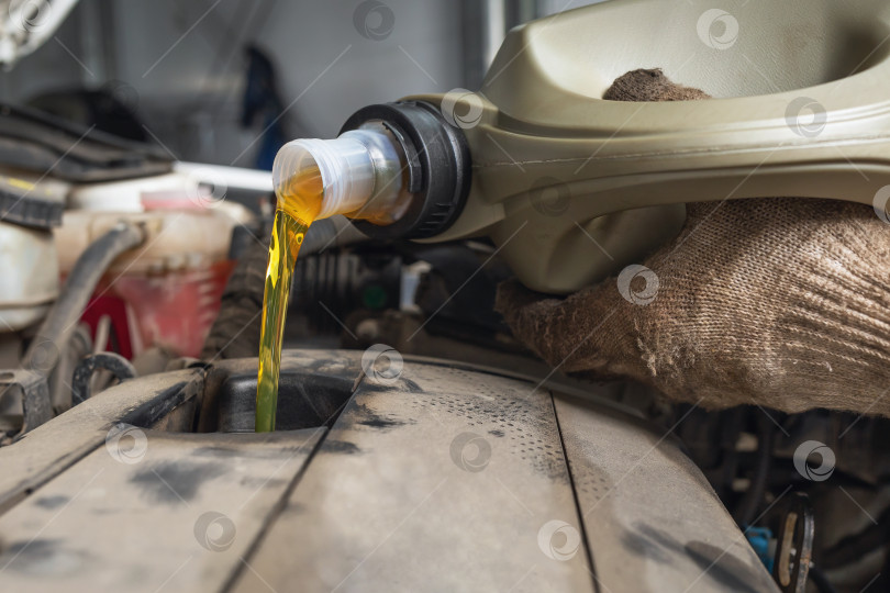 Скачать Автомеханик на станции техобслуживания заливает масло в двигатель автомобиля фотосток Ozero