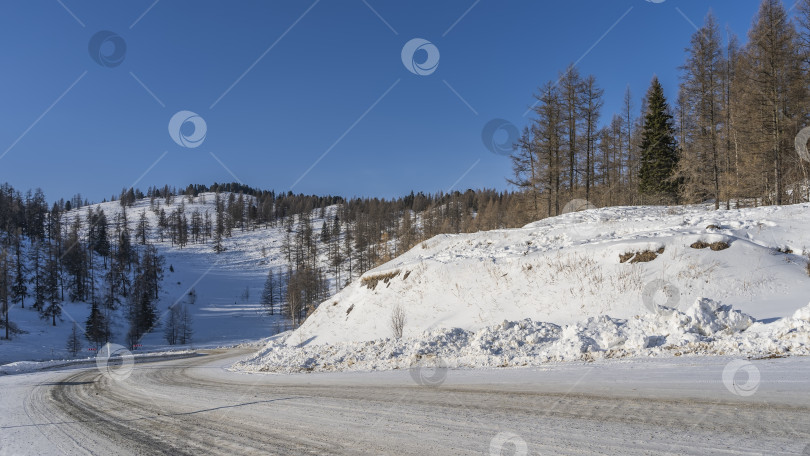 Скачать Шоссе огибает заснеженный холм. фотосток Ozero