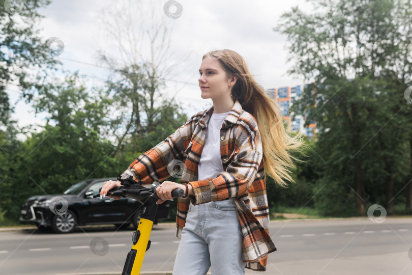 Скачать молодая женщина на электрическом скутере едет по улице фотосток Ozero