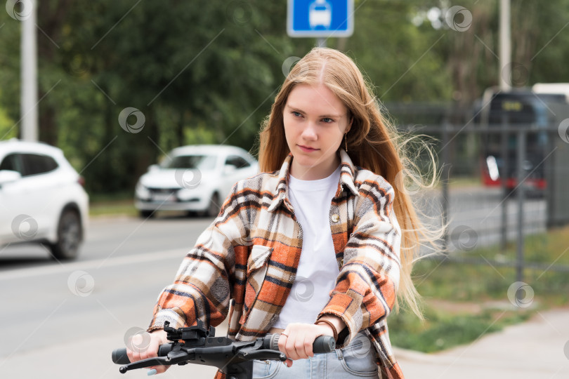Скачать молодая женщина на электрическом скутере едет по улице фотосток Ozero