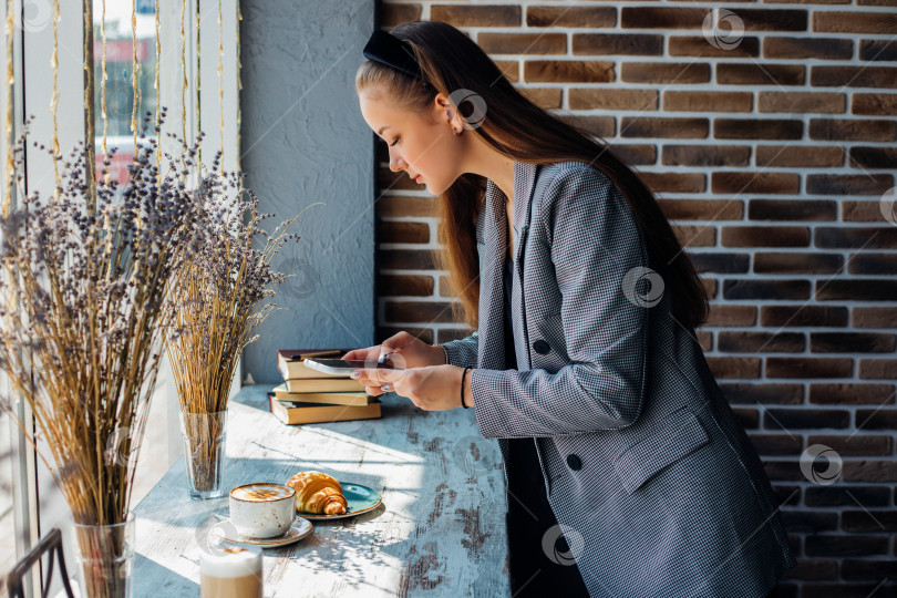 Скачать Концепция "Люди, досуг и технологии": молодая женщина фотографирует сладкий десерт на мобильный телефон. фотосток Ozero