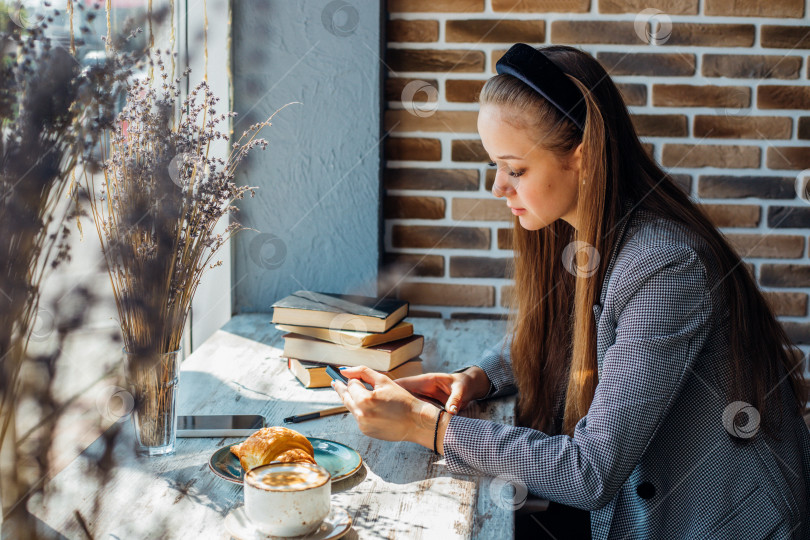 Скачать Красивая молодая женщина использует планшет, чтобы читать информацию или переписываться с друзьями за столиком в кафе. фотосток Ozero