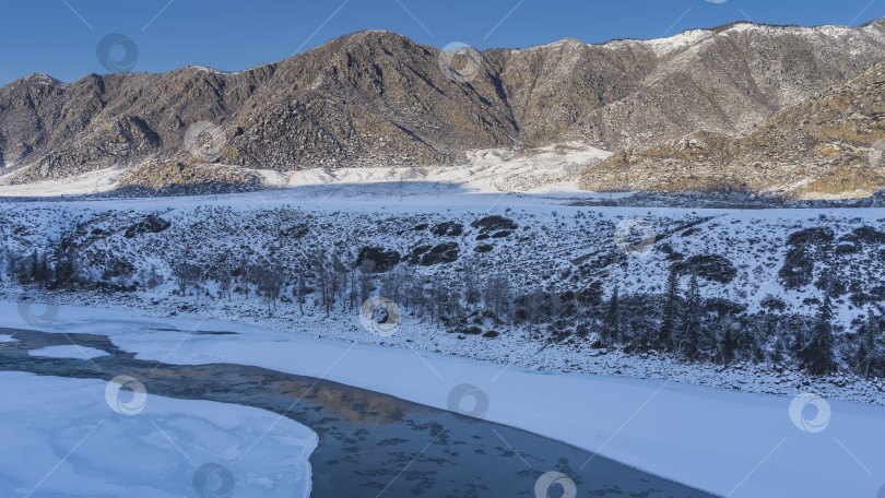 Скачать Незамерзающая река течет по ледяному руслу. фотосток Ozero