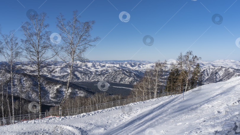 Скачать Забор установлен вдоль заснеженного склона холма. фотосток Ozero