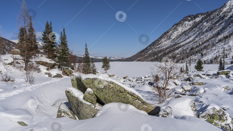 Скачать В долине, под слоем снега, находятся живописные валуны. фотосток Ozero