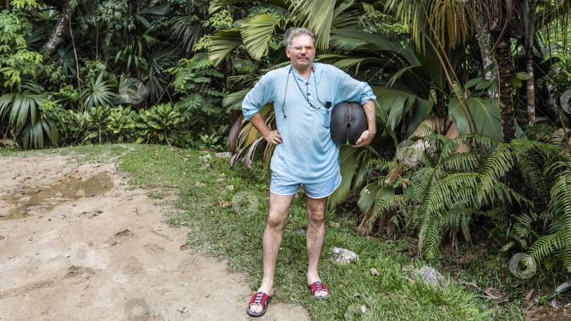 Скачать Мужчина стоит на фоне тропической растительности и улыбается. фотосток Ozero