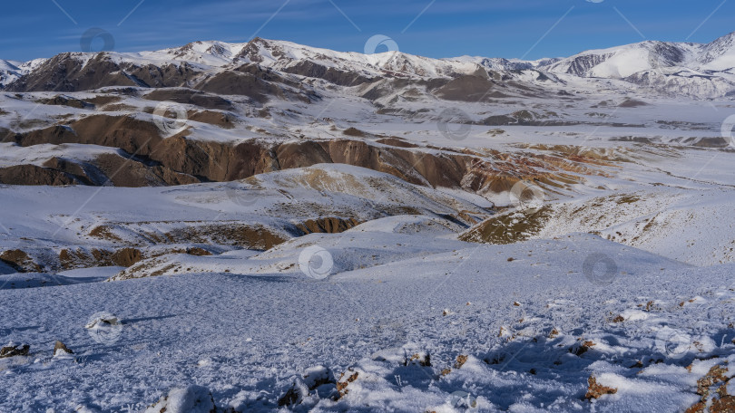 Скачать Заснеженные горы с красно-коричневыми склонами на фоне голубого неба. фотосток Ozero