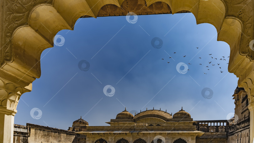 Скачать Сквозь фигурную арку старинного дворца, украшенную орнаментом, видна крыша здания с куполами и шпилями. фотосток Ozero