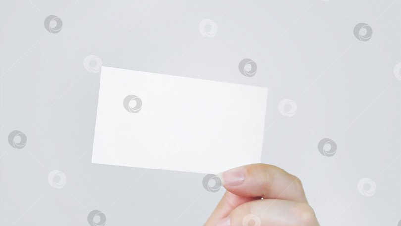Скачать Белый лист визитной карточки в руке на сером фоне. Рука держит визитную карточку. Бизнес-концепция. фотосток Ozero