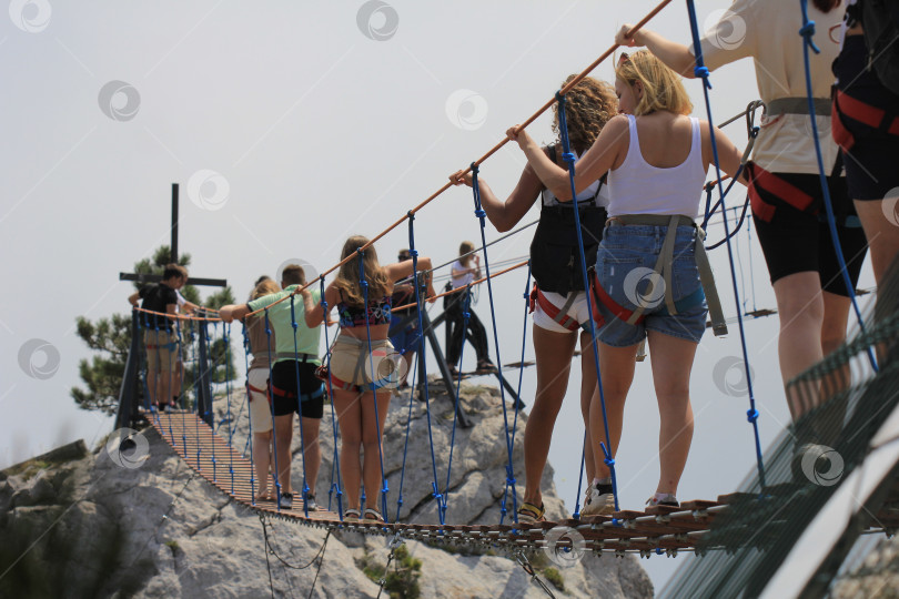 Скачать Толпа людей  на подвесном мосту между скал в горах фотосток Ozero