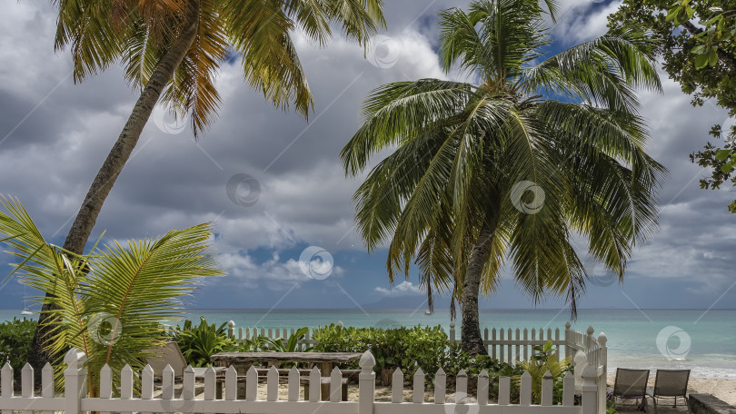 Скачать Зона отдыха на тропическом пляже окружена белым забором. фотосток Ozero