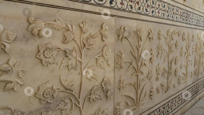 Скачать Детали оформления древнего мавзолея Тадж-Махал. На стене из белого мрамора вырезаны рельефные узоры в виде цветов, листьев, виноградных лоз, орнамент, инкрустированный драгоценными камнями. фотосток Ozero