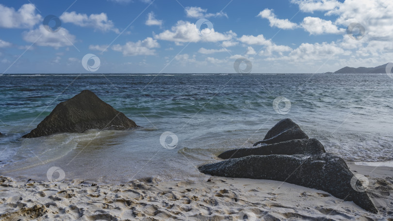Скачать Живописные треугольные гранитные валуны в полосе прибоя на тропическом пляже. фотосток Ozero