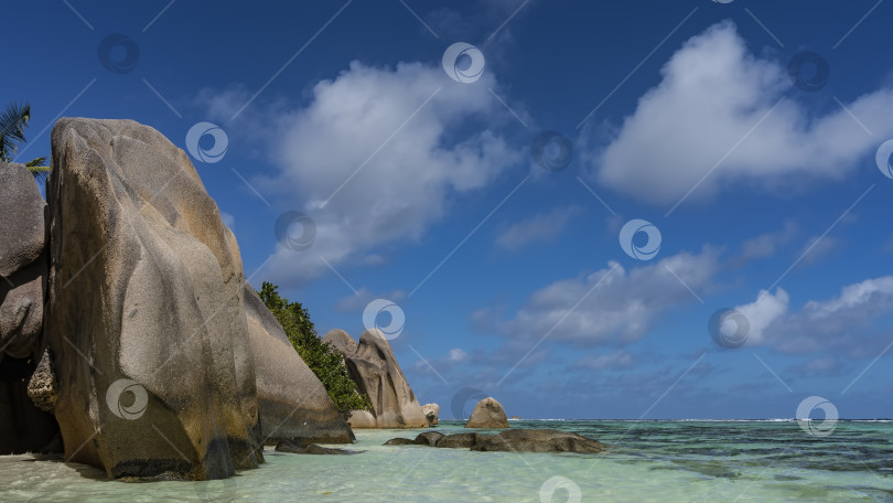 Скачать Живописные гранитные скалы со сглаженными складчатыми крутыми склонами находятся на пляже тропического острова. фотосток Ozero