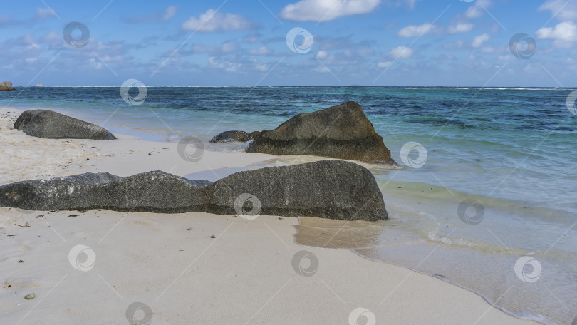 Скачать Гранитные валуны на песчаном пляже омываются волнами бирюзового океана. фотосток Ozero