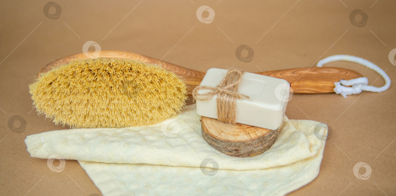 Скачать Деревянная щетка для сухого массажа тела и натуральное мыло лежат на полотенце. Щетка для ног и пемза для пяток. фотосток Ozero