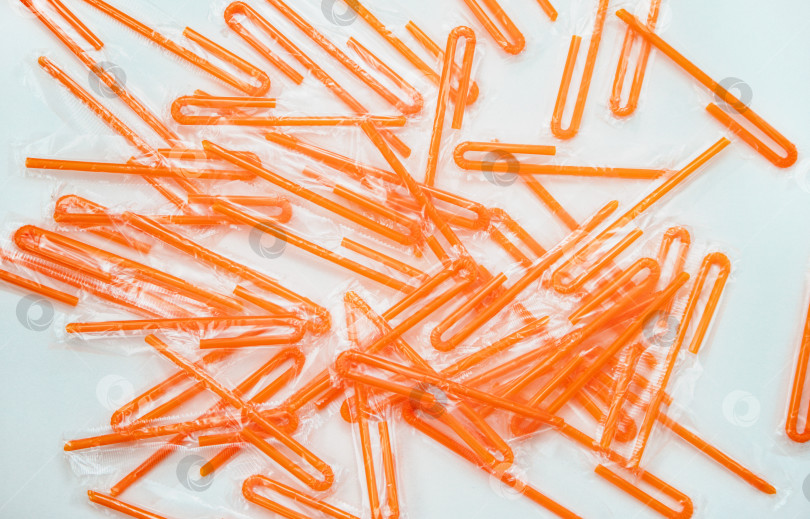 Скачать Пластиковые оранжевые соломинки для коктейлей на белом фоне.Концепция неэкологичного материала. фотосток Ozero