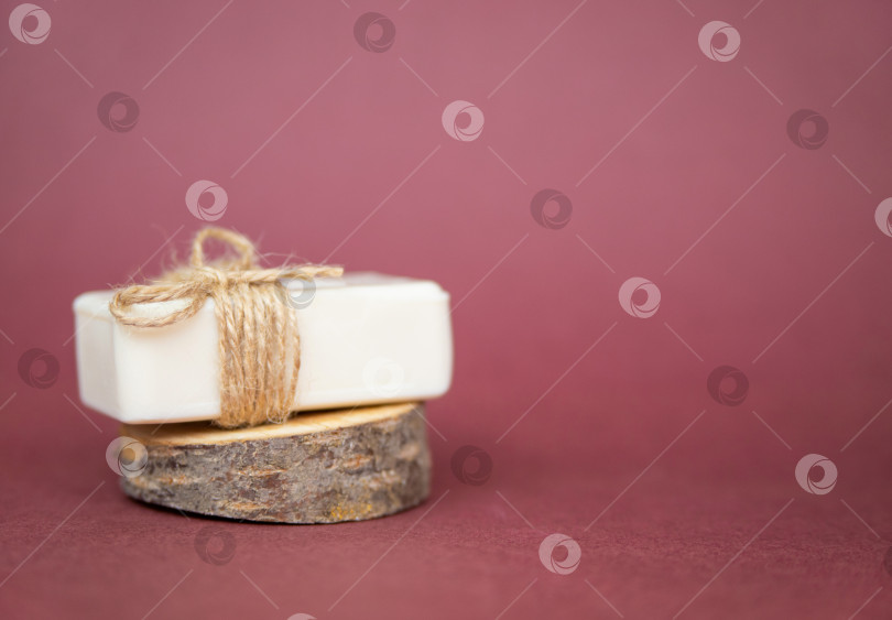 Скачать Кусок белого мыла лежит на срезе дерева на бордовом фоне. Натуральный органический продукт. фотосток Ozero