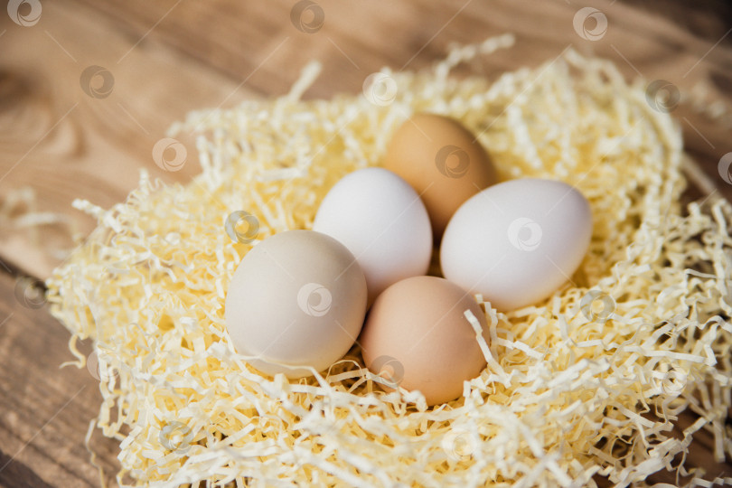 Скачать Пасхальные яйца натурального цвета в гнезде на деревянном фоне. Подготовка к празднику Пасхи. фотосток Ozero