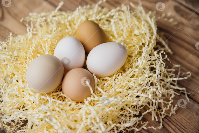 Скачать Пасхальные яйца натурального цвета в гнезде на деревянном фоне. Подготовка к празднику Пасхи. фотосток Ozero