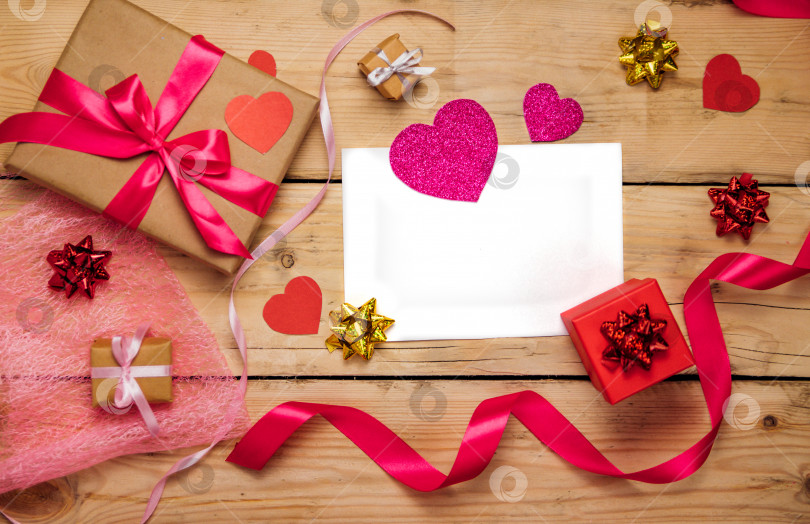 Скачать Фотография подарочной коробки с декором на день Святого Валентина, бумажное сердце, лист бумаги на деревянном фоне с видом сверху. фотосток Ozero