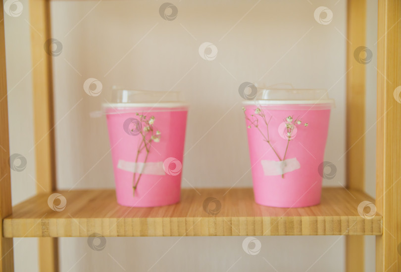 Скачать Многоразовая стильная экологически чистая розовая бамбуковая чашка на деревянной полке. Сокращение количества пластиковых отходов. Чашка, украшенная белыми цветами. Вкусный завтрак. фотосток Ozero