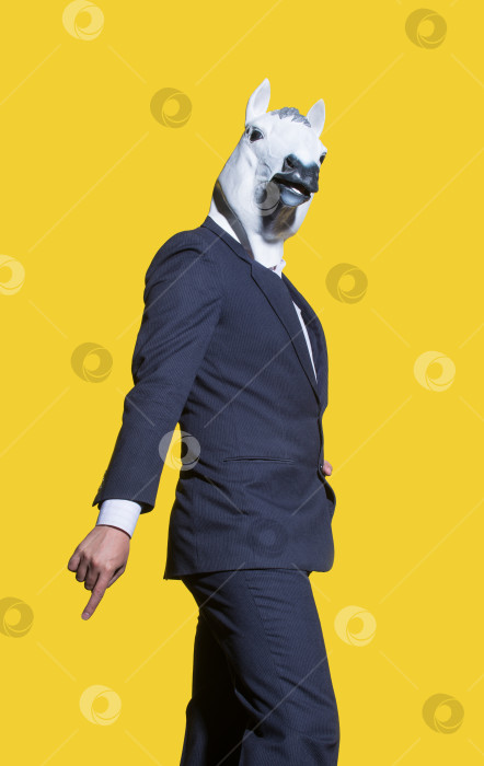 Скачать Вертикальный снимок мужчины в костюме с белой лошадиной маской, позирующего на желтом фоне стены. фотосток Ozero