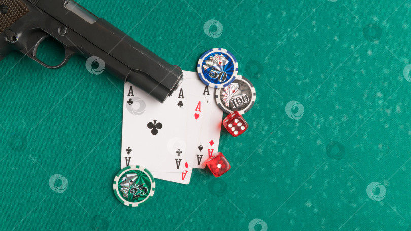 Скачать Верхний снимок оружия рядом с несколькими игральными картами и кубиками на доске для покера. фотосток Ozero